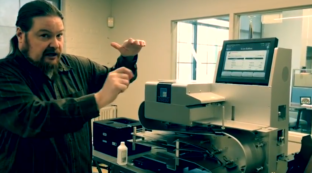 Brian Cleary, Manager of Ballot Preparation and Tabulation for Cuyahoga County, showing election transparency advocate John Brakey the operation of the DS850 digital ballot scanner on March 29, 2018.